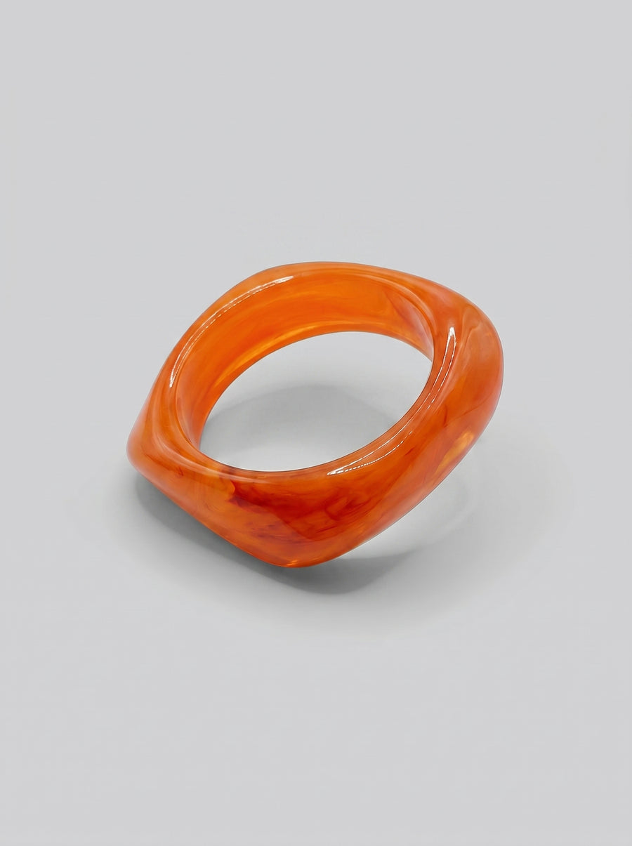 Pulseira Pôr do Sol em resina marmoreada nos tons pôr do sol, coral e laranja, com design orgânico geométrico e acabamento brilhante, ideal para um look elegante e contemporâneo.
