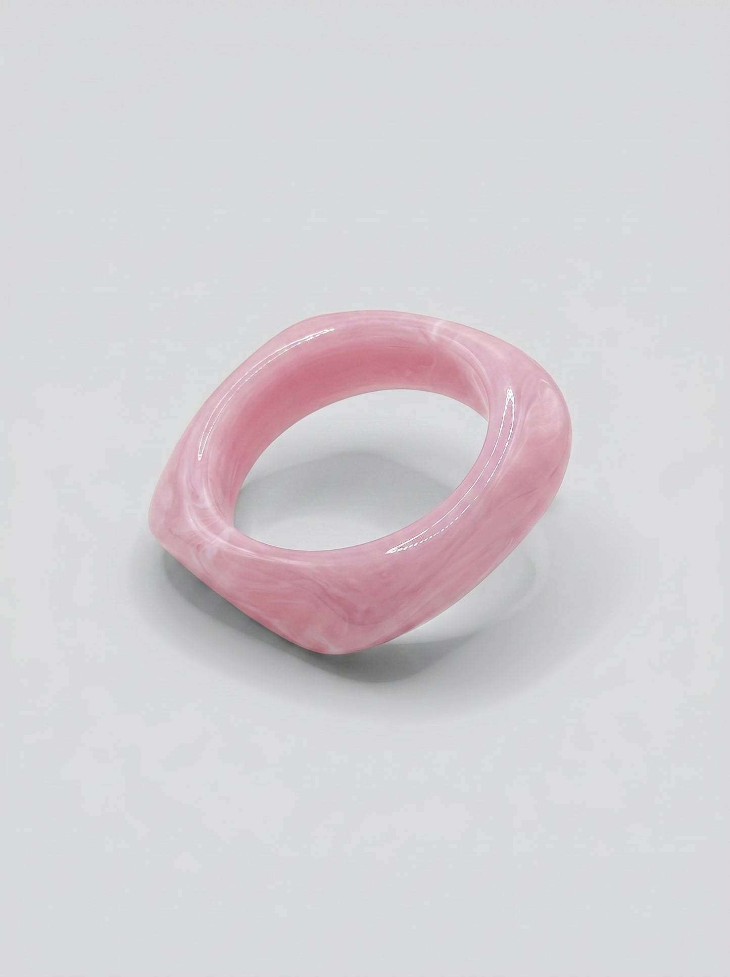 Pulseira Quartzo Rosa em resina marmoreada nos tons quartzo rosa e blush, com design orgânico geométrico e acabamento brilhante, ideal para um look elegante e contemporâneo.
