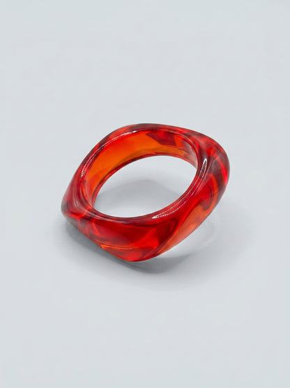 Pulseira Ruby em resina marmoreada nos tons ruby e vermelho intenso, com design orgânico geométrico e acabamento brilhante, ideal para um look elegante e contemporâneo.

