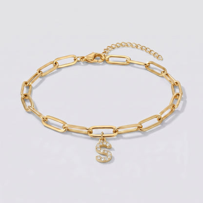 Pulseira dourada com letra inicial S, corrente paperclip e pendente de letra cravejado.