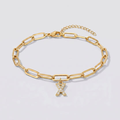 Pulseira dourada com letra inicial X, corrente paperclip e pendente de letra cravejado.