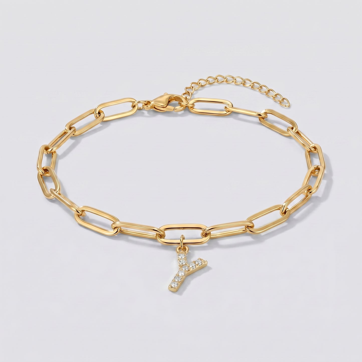 Pulseira dourada com letra inicial Y, corrente paperclip e pendente de letra cravejado.