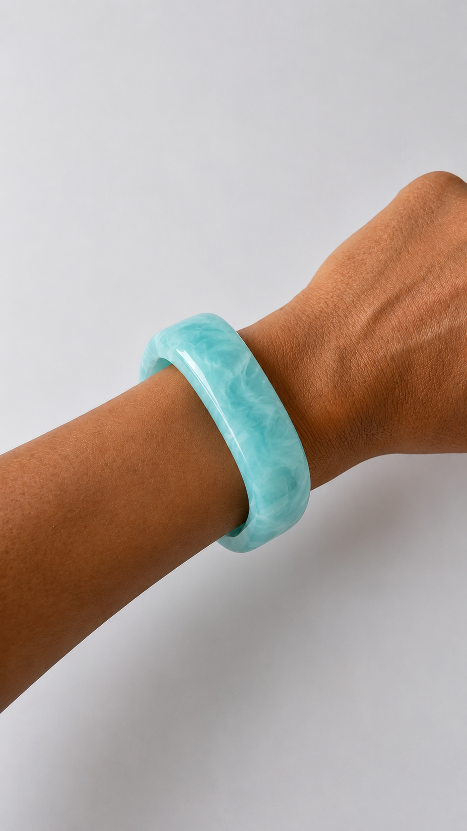 Pulseira de resina azul turquesa usada no pulso, com acabamento brilhante e estilo elegante.