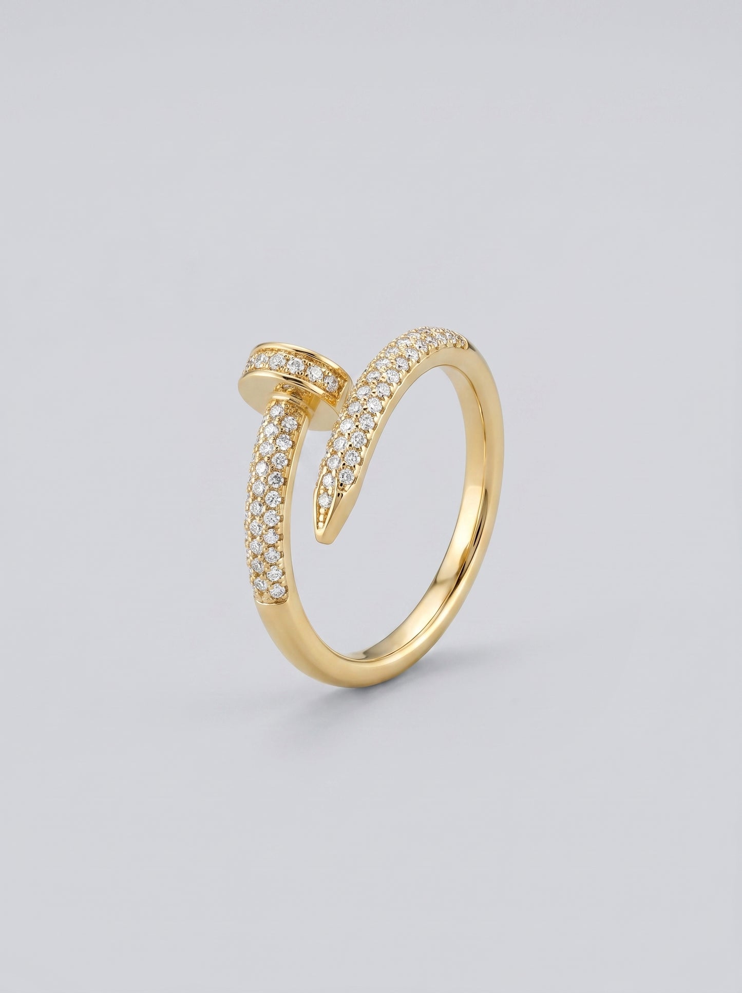 Anel em ouro com detalhes em diamante sobre fundo cinza claro.

