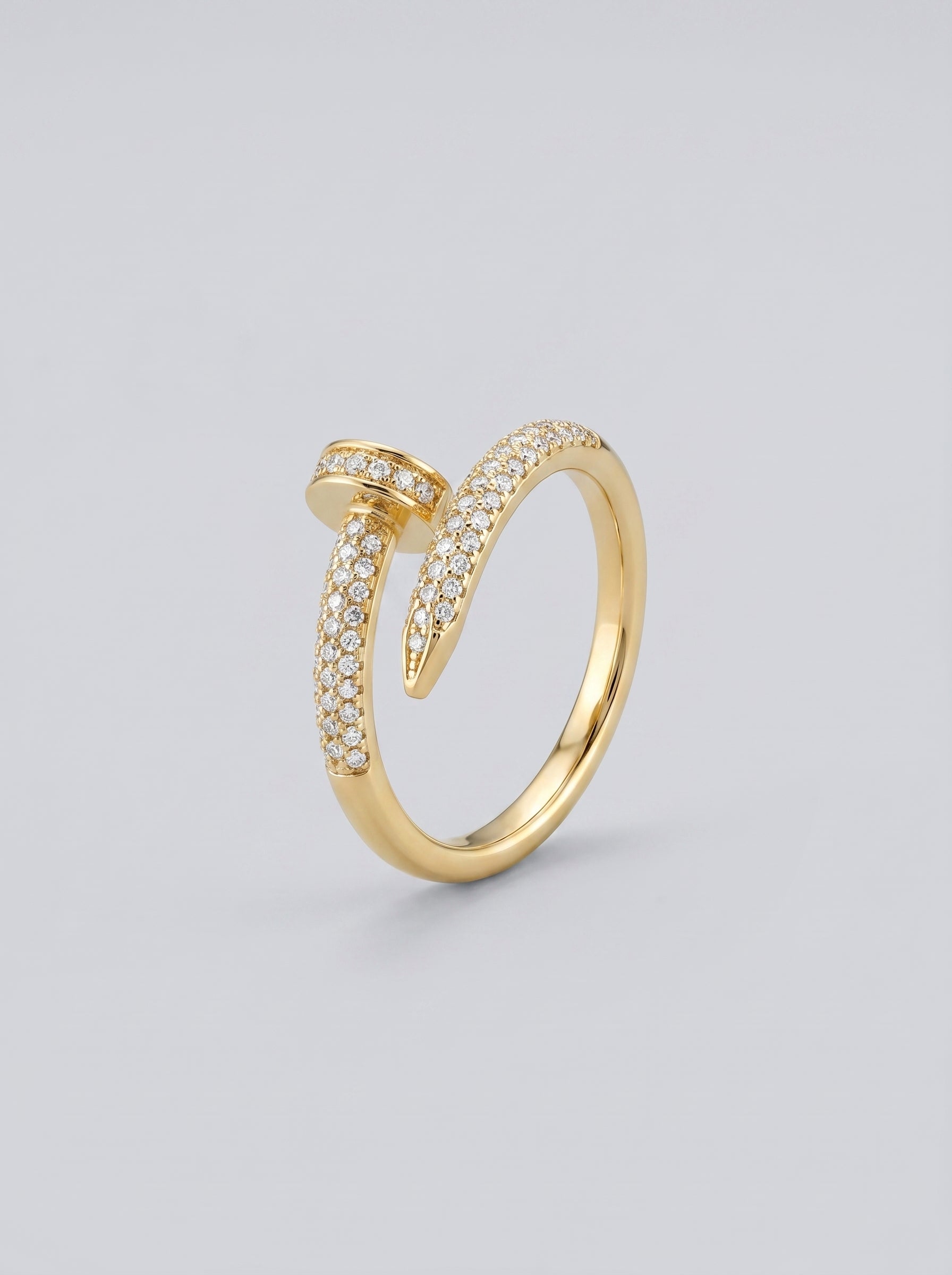 Anel em ouro com detalhes em diamante sobre fundo cinza claro.
