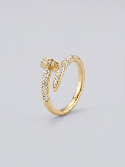 Anel em ouro com detalhes em diamante sobre fundo cinza claro.
