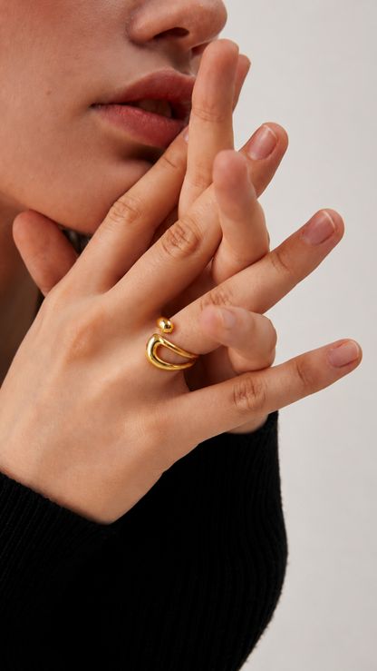 Anel dourado moderno com design orgânico usado por modelo em close-up elegante.