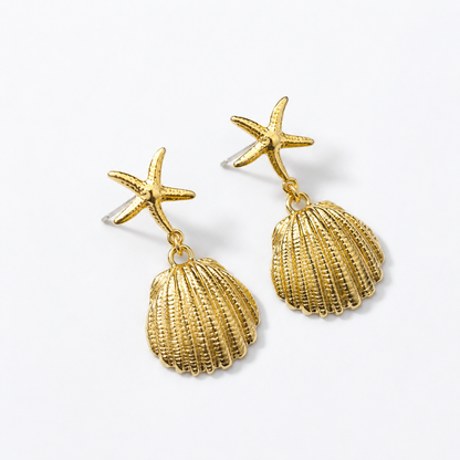 Brincos dourados com estrela-do-mar texturizada e pingente de concha, fotografados sobre fundo claro para um visual elegante e inspirado no mar.