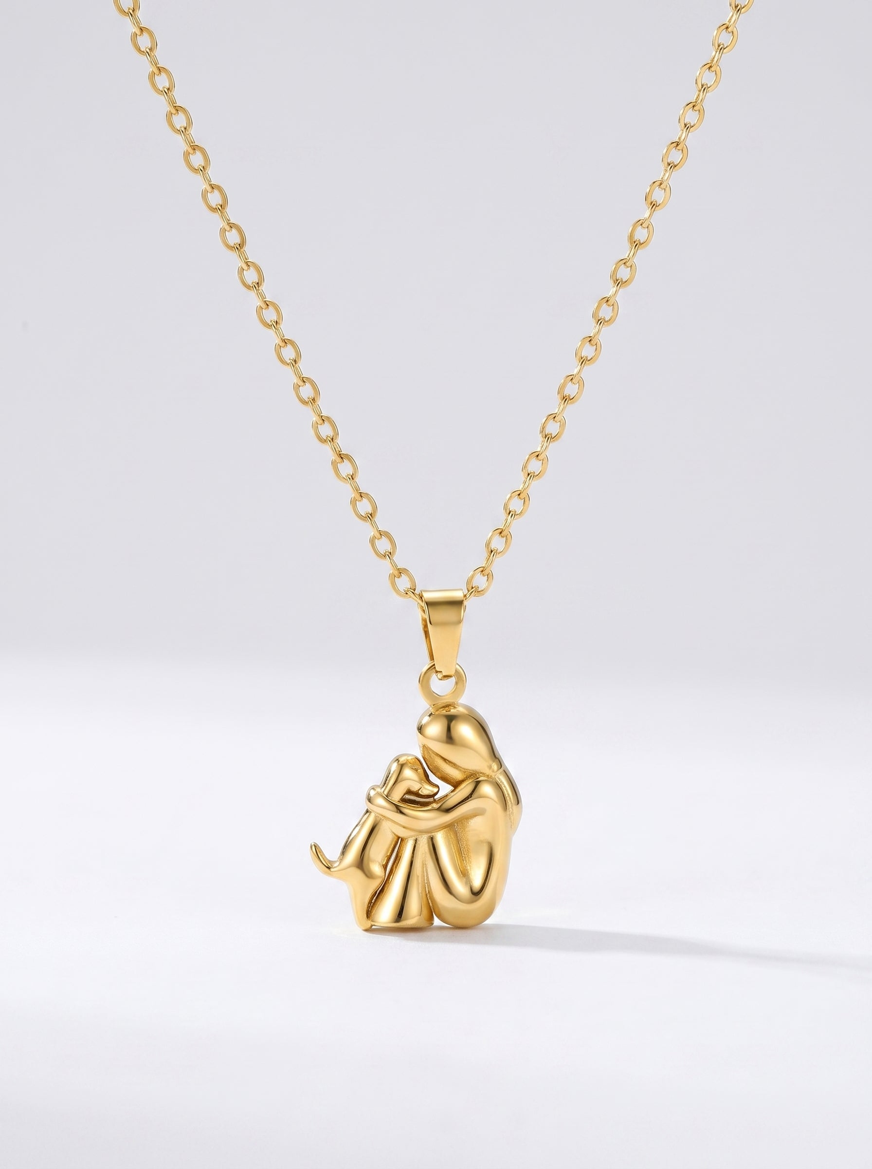 Colar dourado delicado com pendente artístico abstrato e acabamento brilhante, fotografado sobre fundo claro para um visual elegante, moderno e sofisticado.