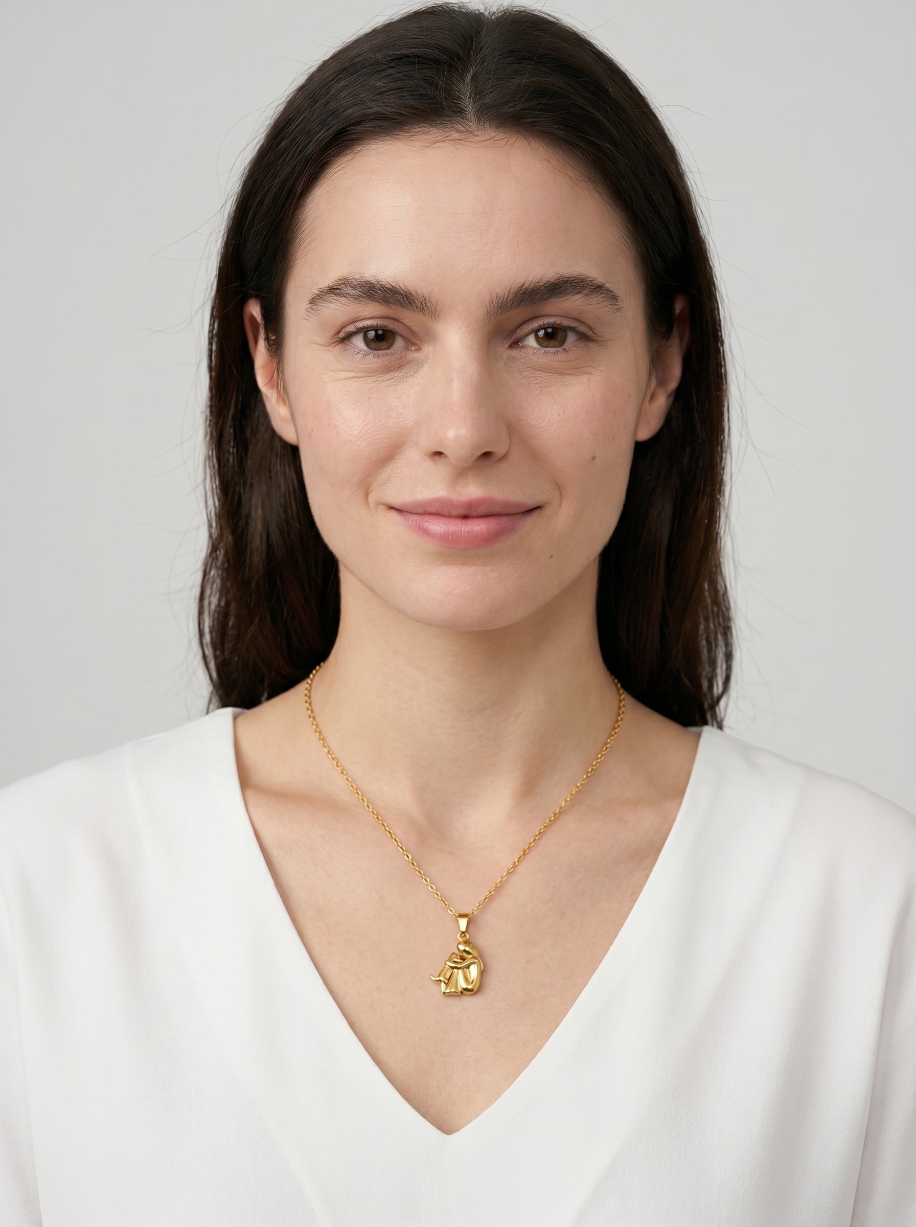 Colar dourado delicado com pendente artístico abstrato e acabamento brilhante, usado por uma modelo para um visual elegante, moderno e sofisticado.