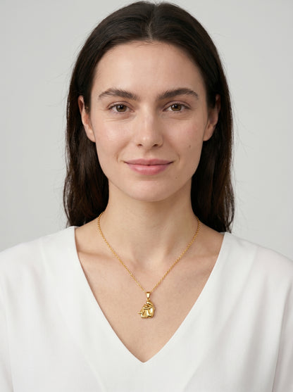 Colar dourado delicado com pendente artístico abstrato e acabamento brilhante, usado por uma modelo para um visual elegante, moderno e sofisticado.