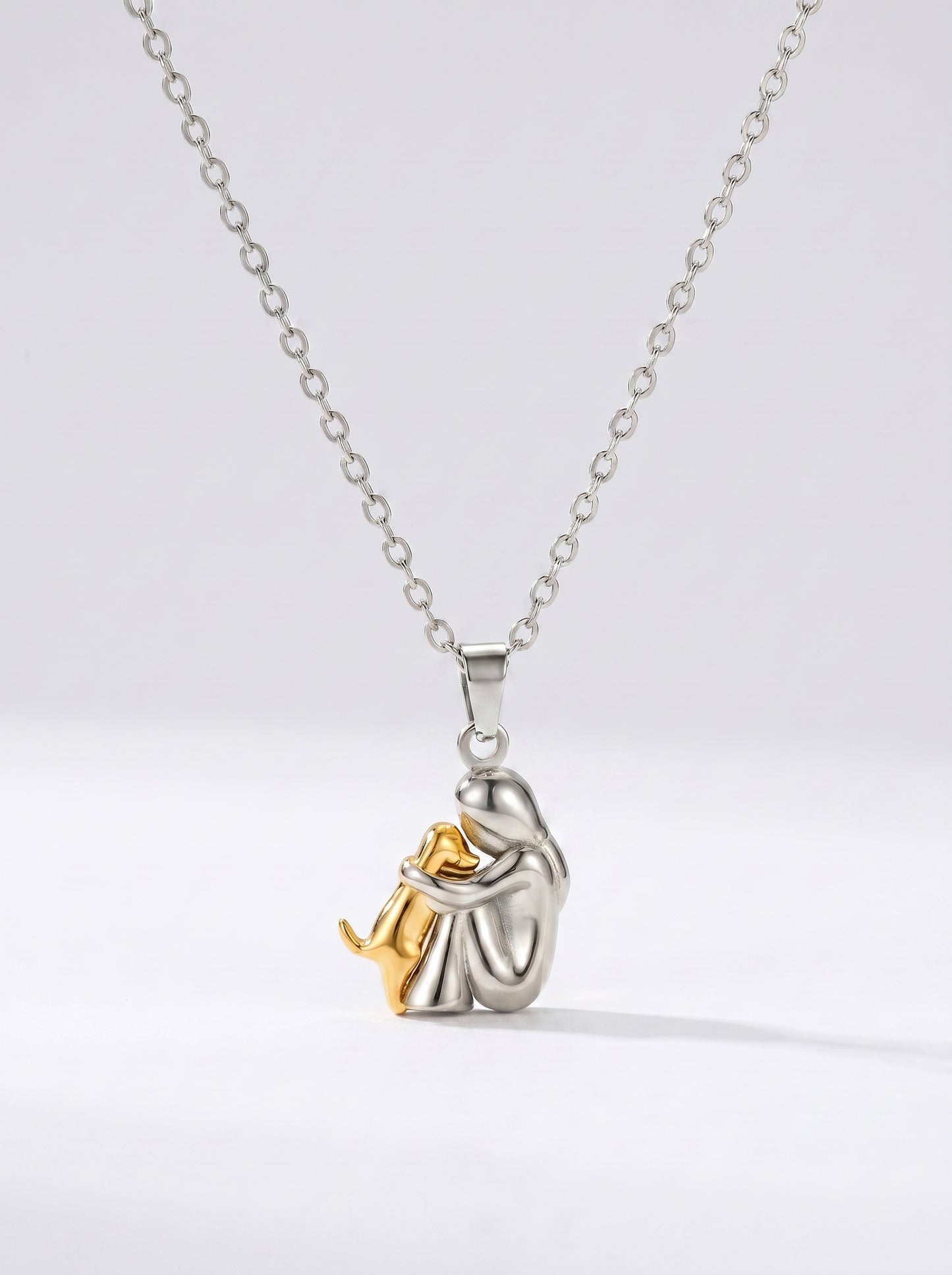 Colar prateado delicado com pendente artístico abstrato em dourado e prata e acabamento brilhante, fotografado sobre fundo claro para um visual moderno, elegante e sofisticado.