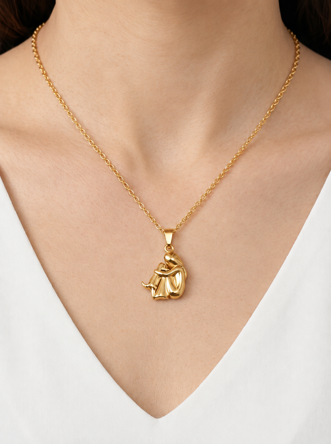 Colar dourado delicado com pendente artístico abstrato e acabamento brilhante, usado ao pescoço para um visual moderno, elegante e sofisticado.