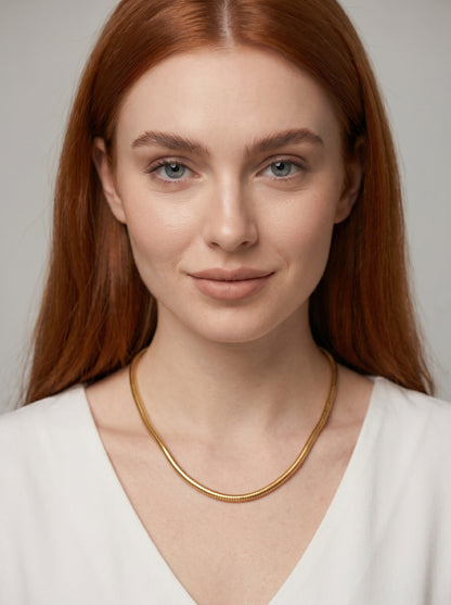Colar dourado moderno com acabamento texturizado e design minimalista, usado por uma modelo para um visual elegante, artístico e sofisticado.
