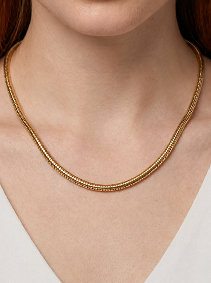 Colar dourado moderno com acabamento texturizado e design minimalista, usado ao pescoço para um visual elegante, artístico e sofisticado.