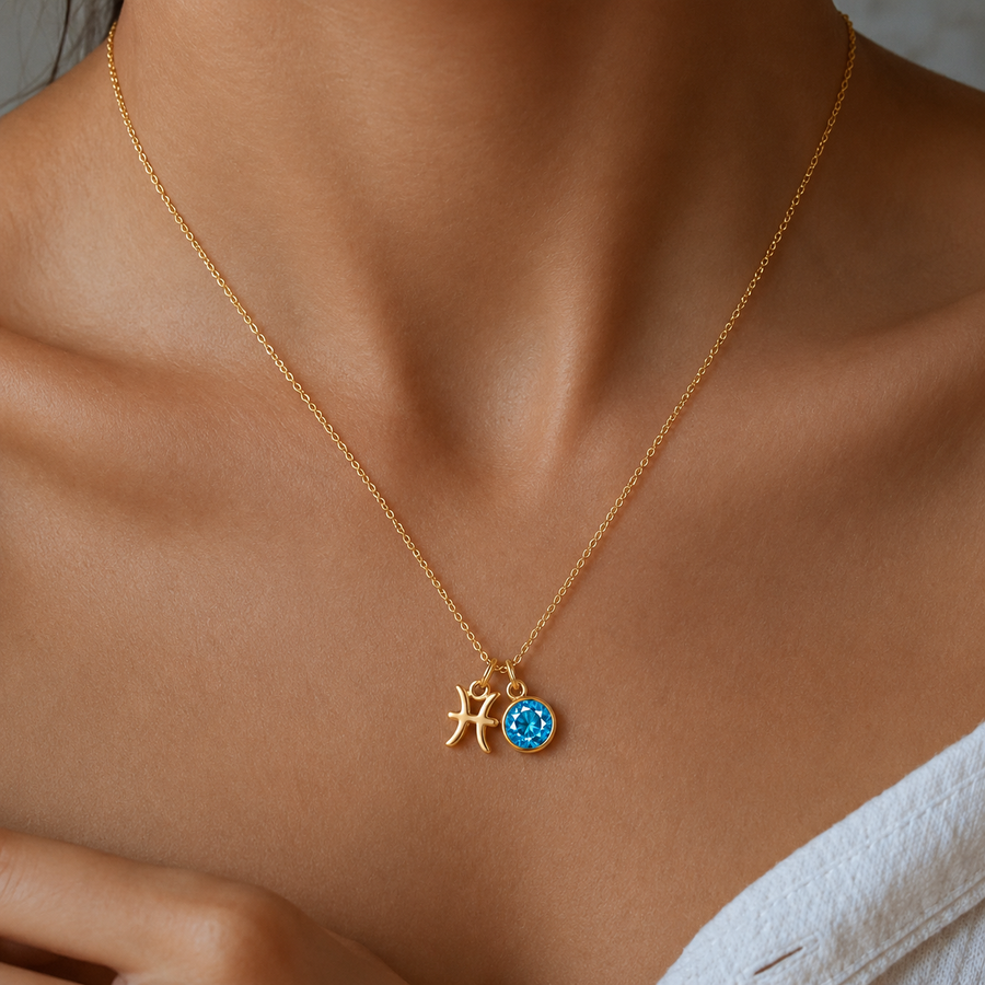 Mulher a usar colar dourado com símbolo do signo Peixes e pedra de nascimento azul, em destaque sobre o pescoço.