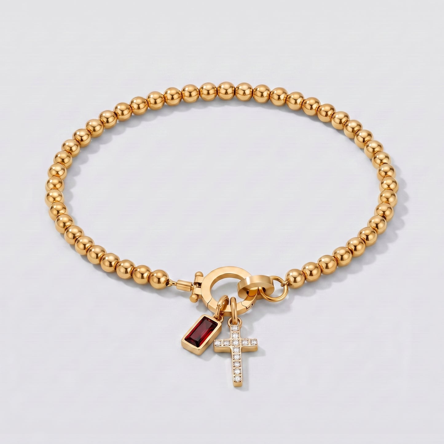 Pulseira dourada de contas com cruz e pedra de nascimento granada de janeiro.