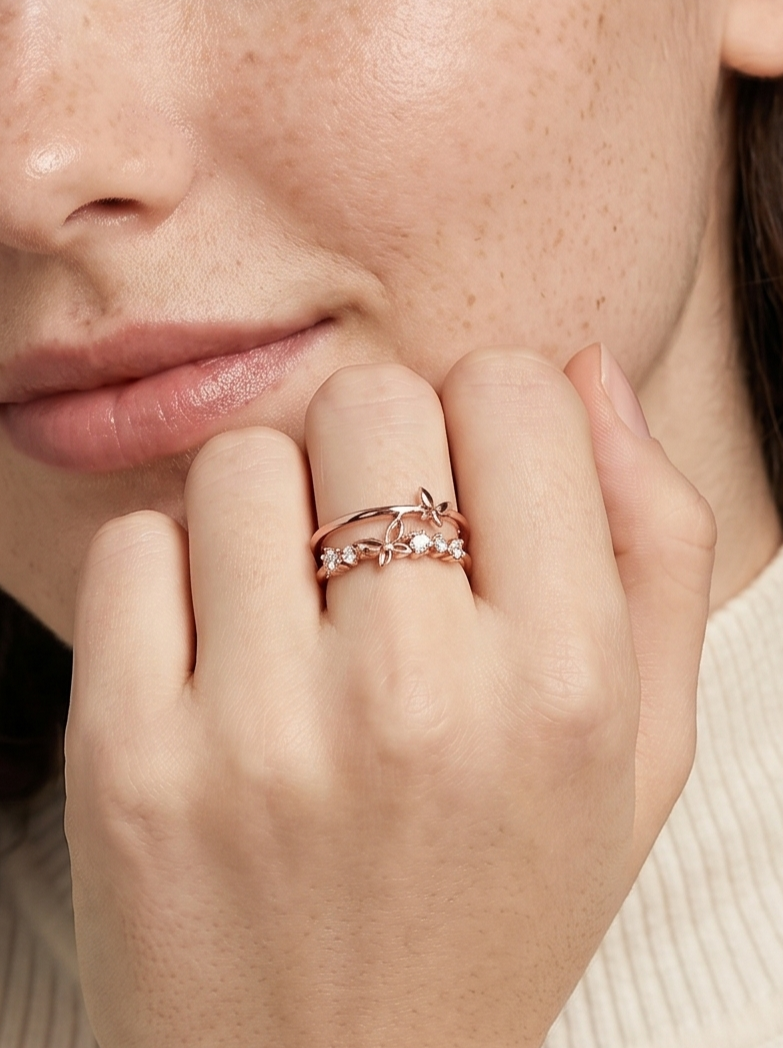 Grande plano de uma mão usando um anel de ouro rosa com um diamante, a tocar no queixo.
