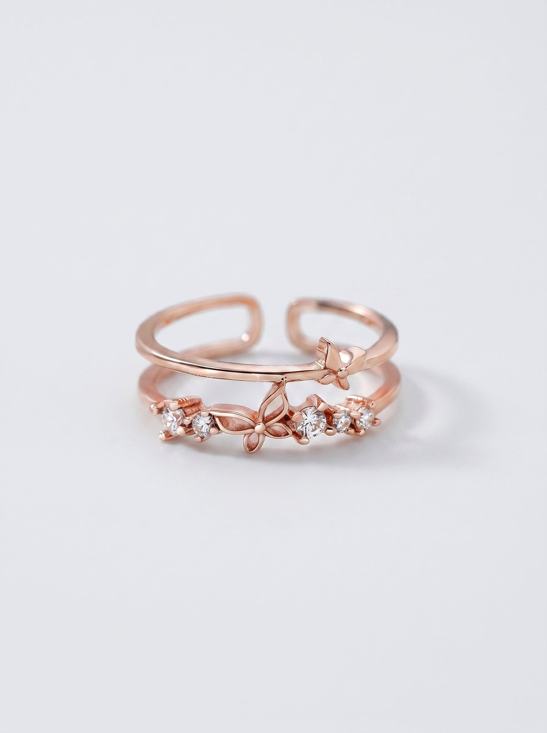 Anel em ouro rosa com detalhes em diamante sobre fundo cinza claro.

