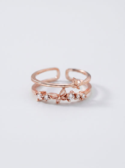 Anel em ouro rosa com detalhes em diamante sobre fundo cinza claro.
