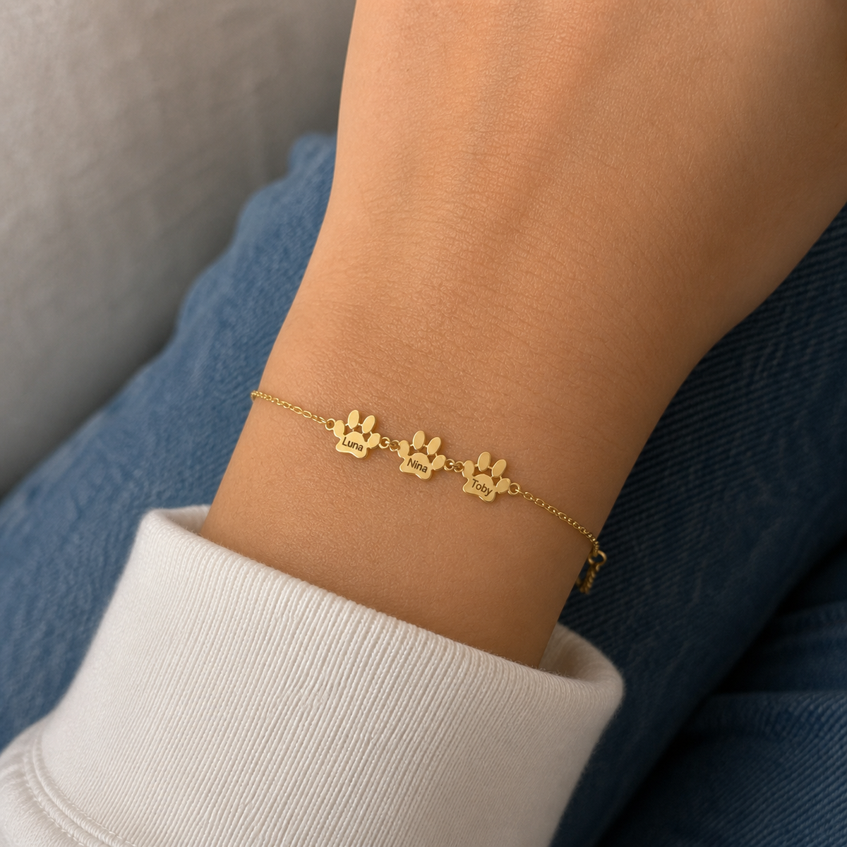 Pulseira com Patas e Nomes dourada — 3 Patas com os nomes Luna, Nina e Toby no pulso — lifestyle realista