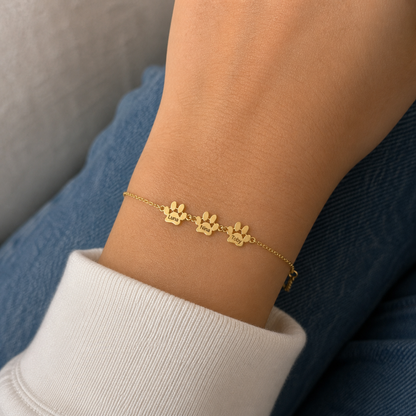 Pulseira com Patas e Nomes dourada — 3 Patas com os nomes Luna, Nina e Toby no pulso — lifestyle realista