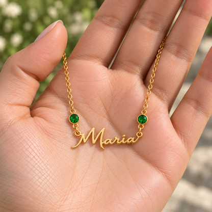 Colar dourado Maria com duas esmeraldas apresentado na mão