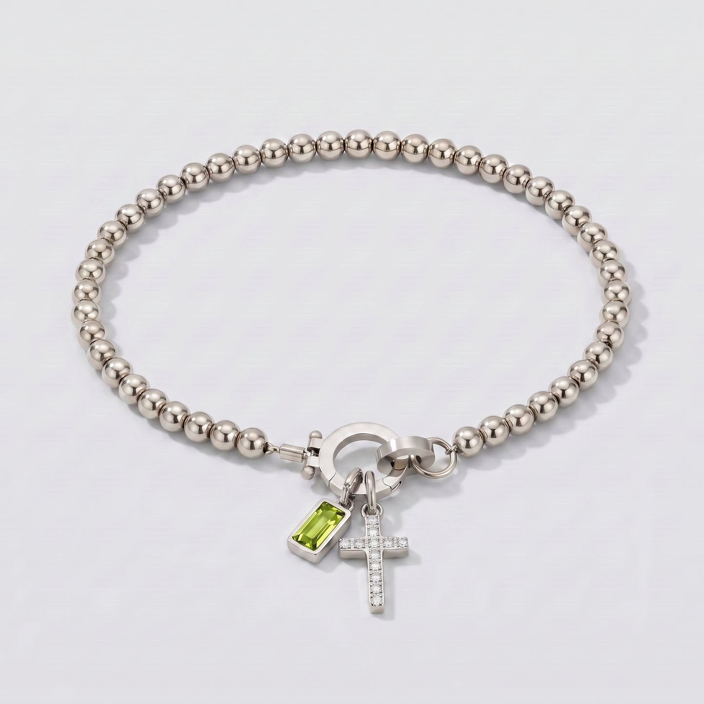 Pulseira prateada de contas com cruz e pedra de nascimento peridoto verde de agosto.