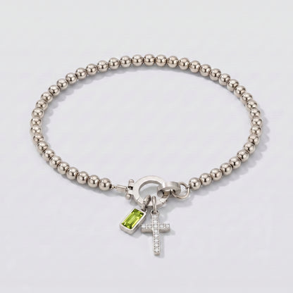 Pulseira prateada de contas com cruz e pedra de nascimento peridoto verde de agosto.