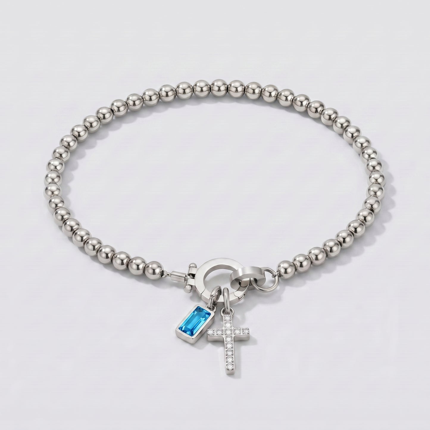 Pulseira prateada de contas com cruz e pedra de nascimento topázio azul de dezembro.