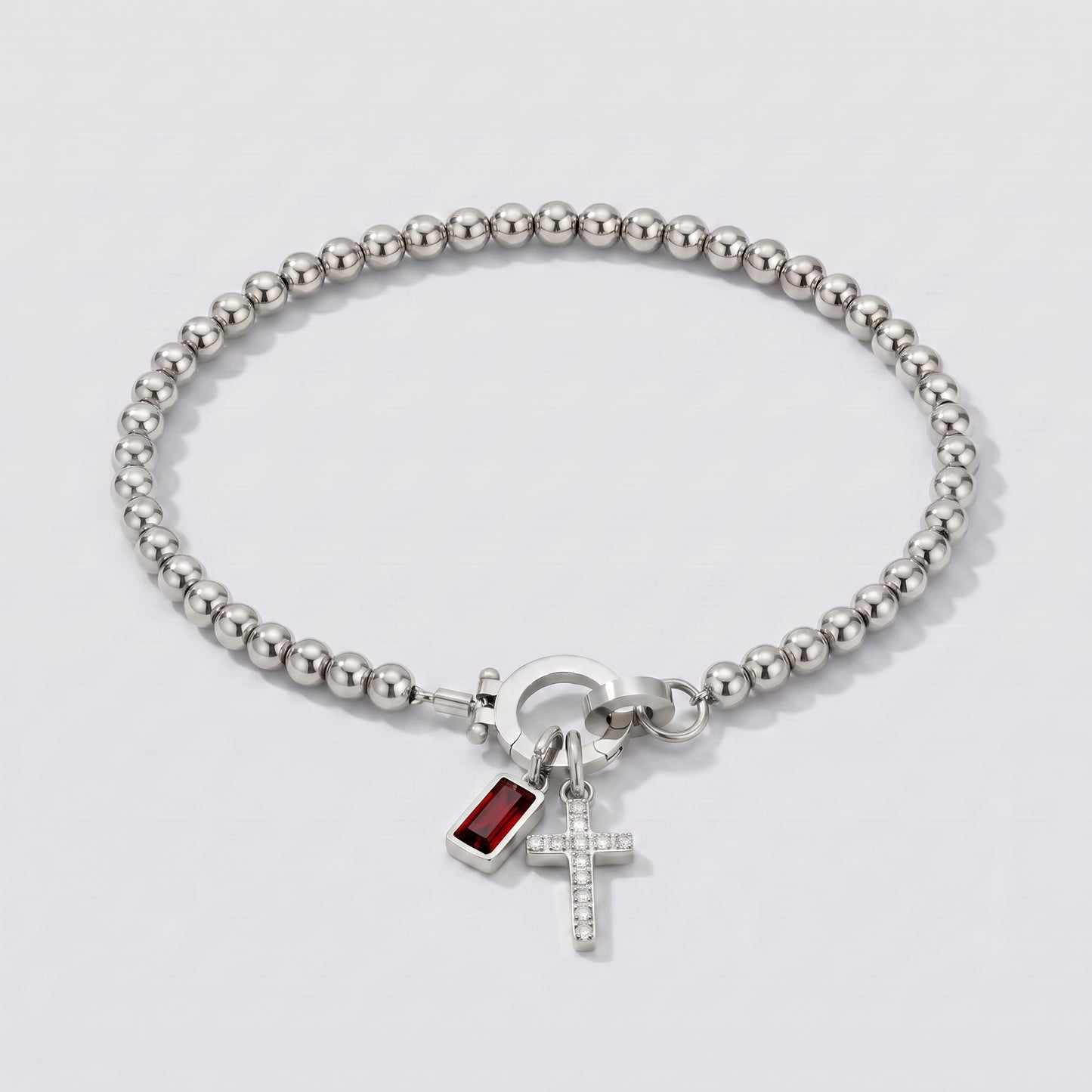 Pulseira prateada de contas com cruz e pedra de nascimento granada vermelha de janeiro.