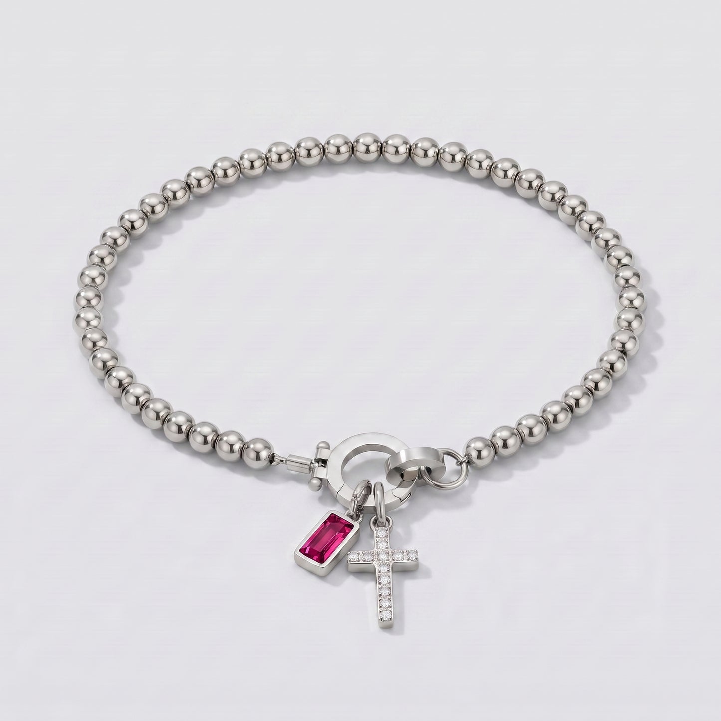 Pulseira prateada de contas com cruz e pedra de nascimento rubi vermelha de julho.