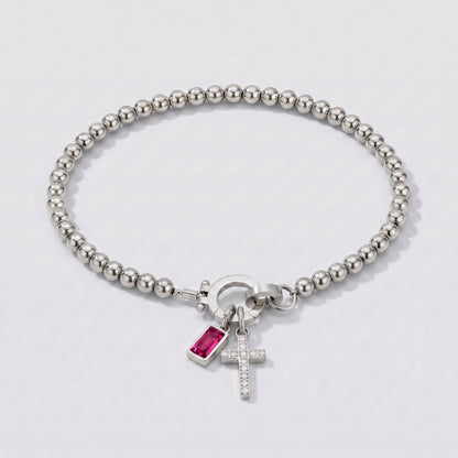 Pulseira prateada de contas com cruz e pedra de nascimento rubi vermelha de julho.