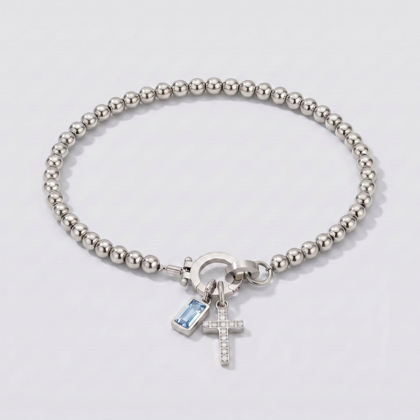 Pulseira prateada de contas com cruz e pedra de nascimento água-marinha azul clara de março.