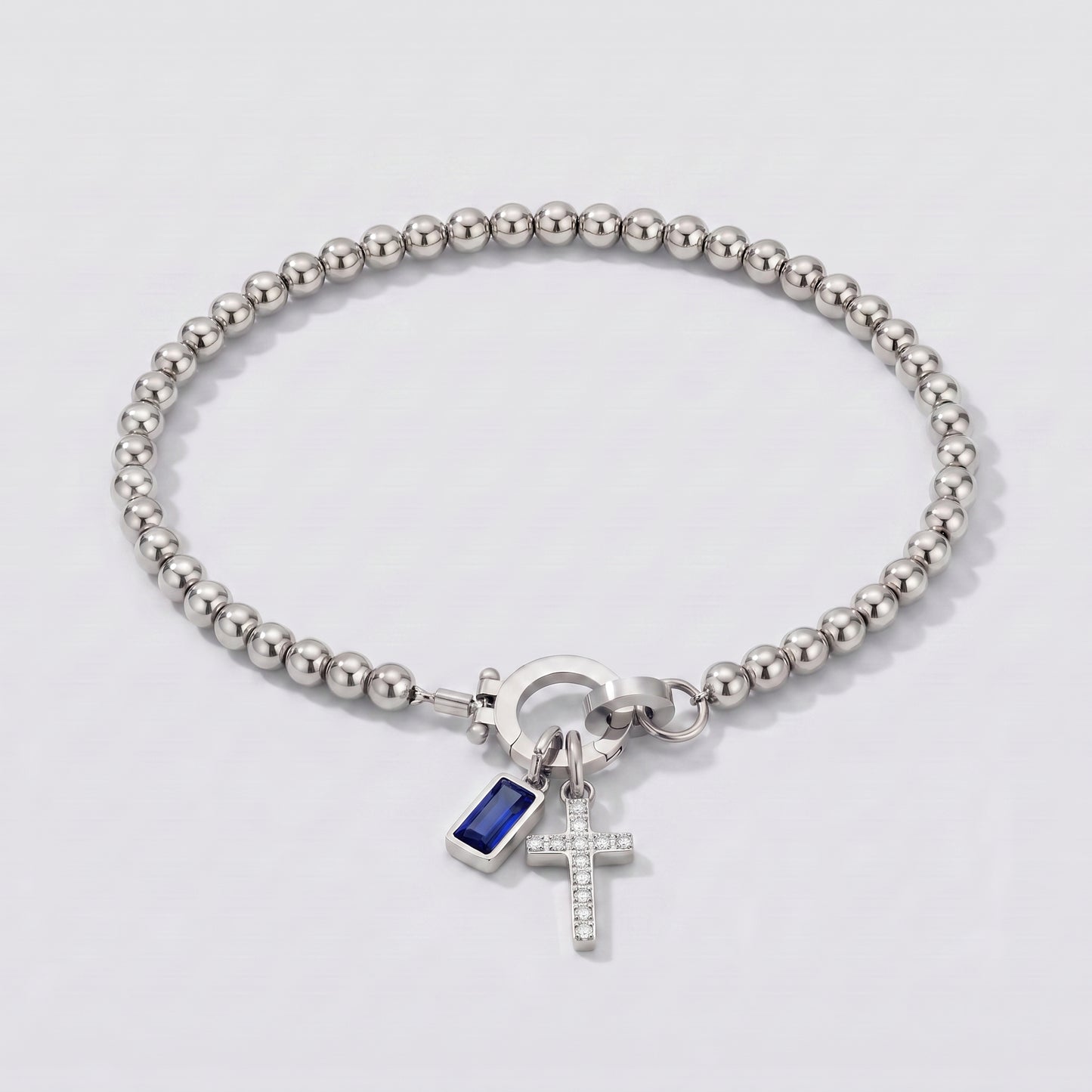 Pulseira prateada de contas com cruz e pedra de nascimento safira azul de setembro.