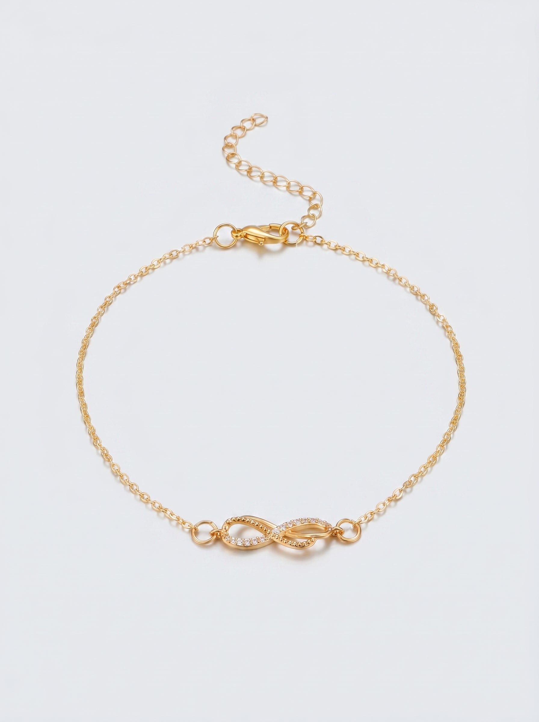 Pulseira dourada delicada com símbolo infinito e acabamento brilhante, fotografada sobre fundo claro para um visual elegante, feminino e minimalista.