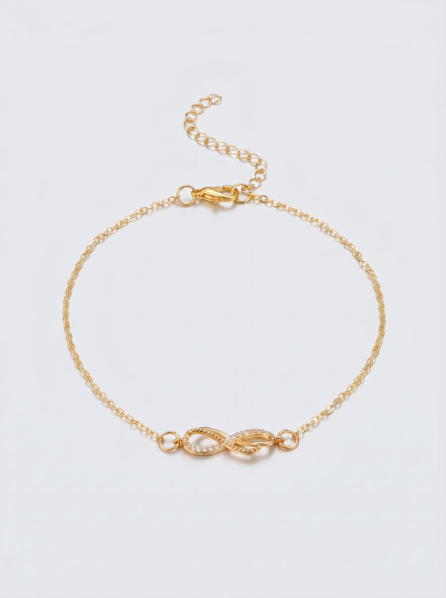 Pulseira dourada delicada com símbolo infinito e acabamento brilhante, fotografada sobre fundo claro para um visual elegante, feminino e minimalista.