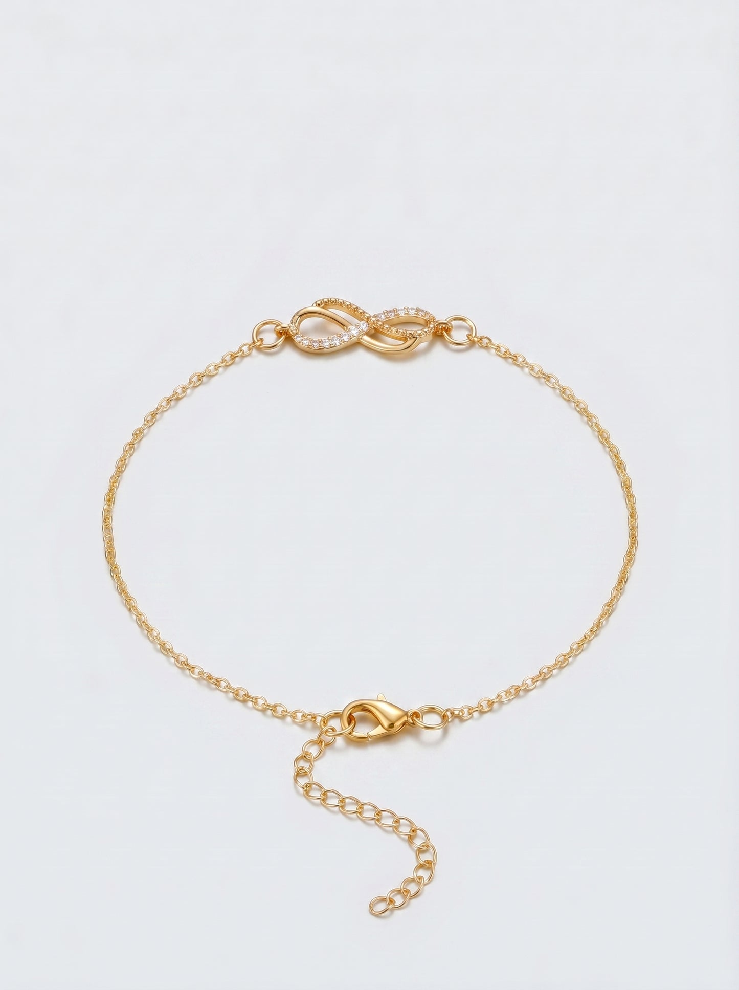 Pulseira dourada delicada com símbolo infinito, corrente fina e fecho ajustável, fotografada sobre fundo claro para um visual elegante, feminino e minimalista.