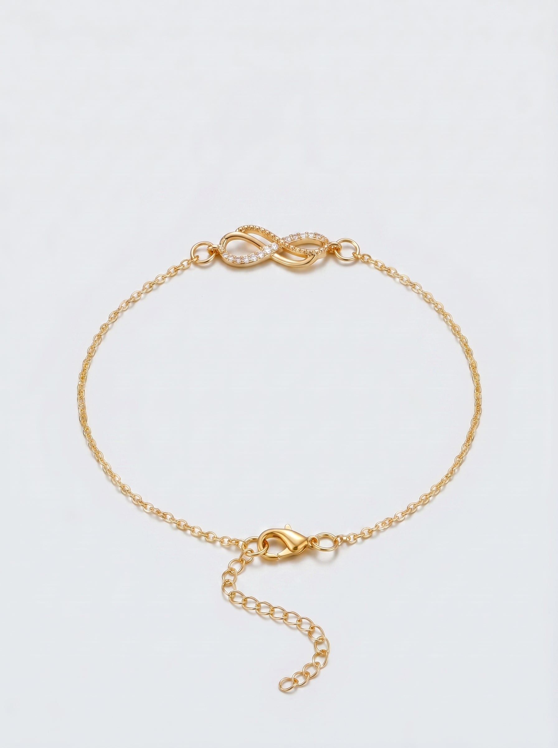 Pulseira dourada delicada com símbolo infinito, corrente fina e fecho ajustável, fotografada sobre fundo claro para um visual elegante, feminino e minimalista.