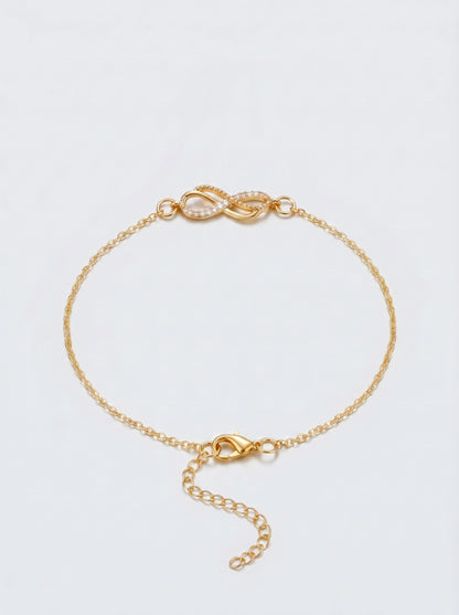 Pulseira dourada delicada com símbolo infinito, corrente fina e fecho ajustável, fotografada sobre fundo claro para um visual elegante, feminino e minimalista.