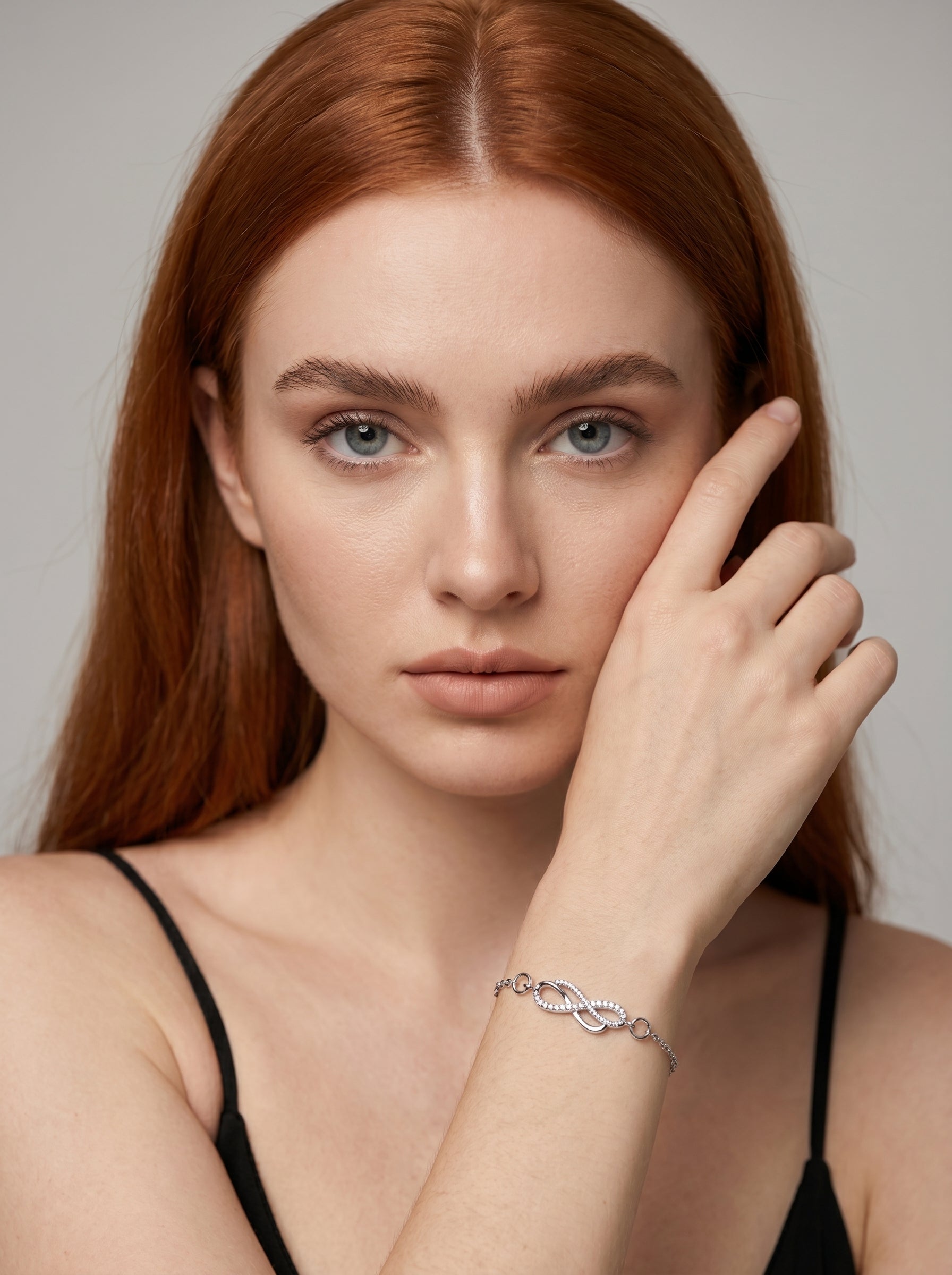 Pulseira prateada delicada com símbolo infinito, detalhe em cristais e corrente fina, usada por uma modelo para um visual elegante, feminino e minimalista.