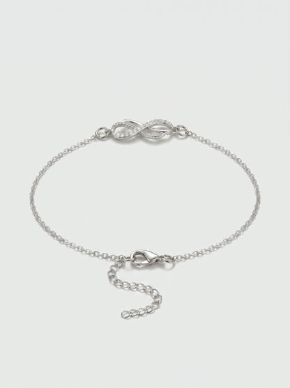 Pulseira prateada delicada com símbolo infinito, detalhe em cristais, corrente fina e fecho ajustável, fotografada sobre fundo claro para um visual elegante, feminino e minimalista.