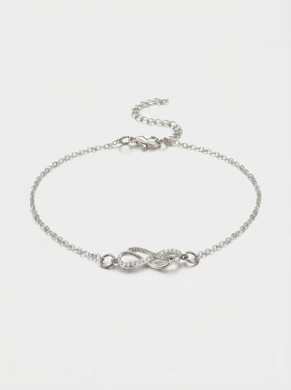 Pulseira prateada delicada com símbolo infinito, detalhe em cristais, corrente fina e fecho ajustável, fotografada sobre fundo claro para um visual elegante, feminino e minimalista.