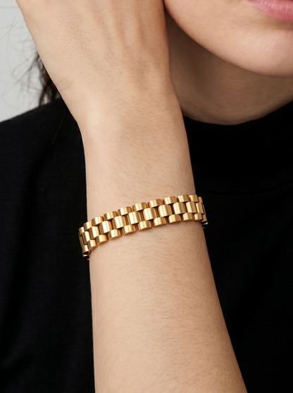 Pulseira dourada com design de elos largos e acabamento brilhante, usada no pulso para um visual elegante e sofisticado.