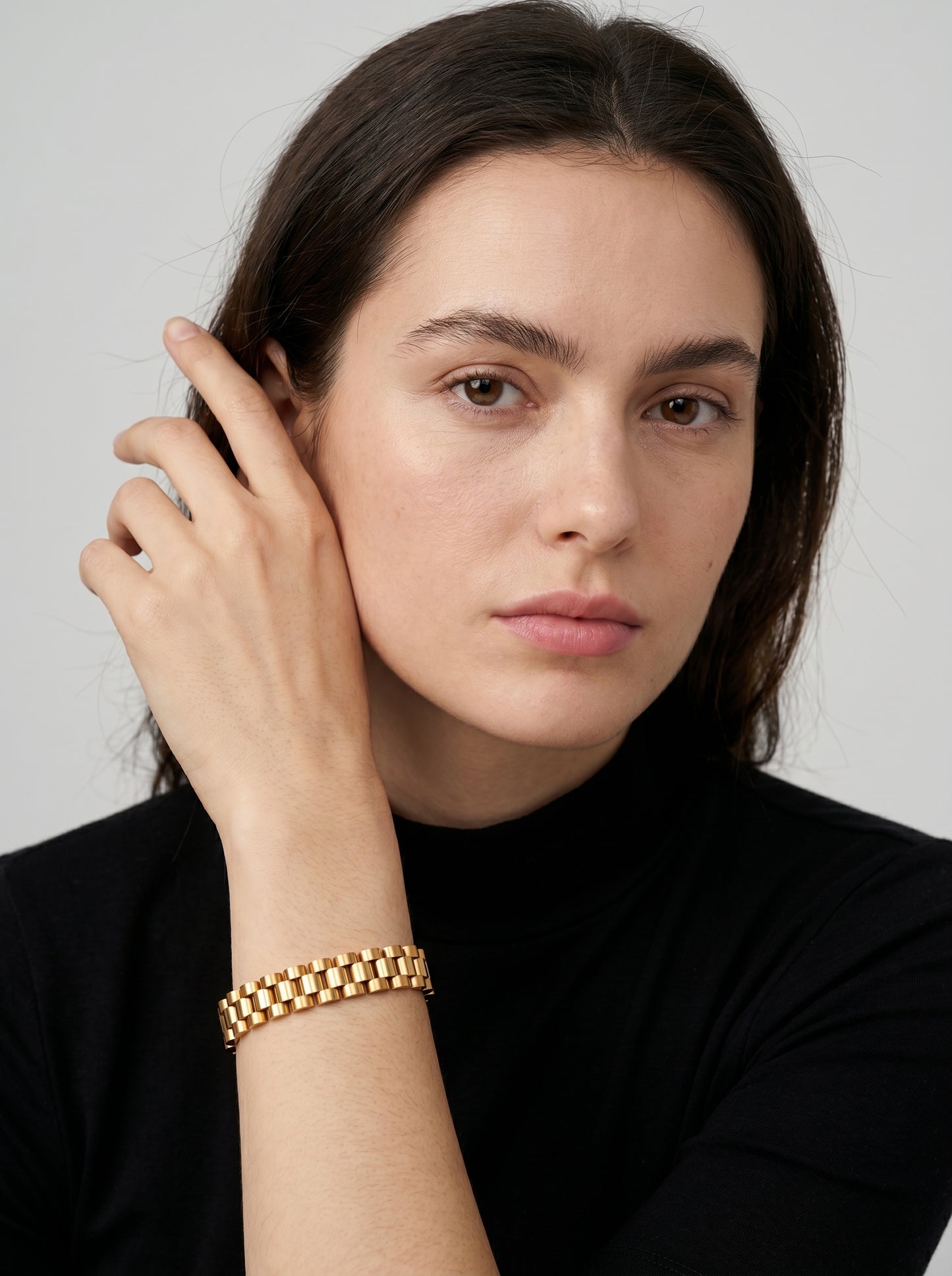 Pulseira dourada com design de elos largos e acabamento brilhante, usada por uma modelo para um visual elegante e sofisticado.
