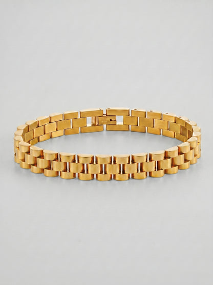 Pulseira dourada com design de elos largos e acabamento polido, fotografada sobre fundo cinzento claro para um visual elegante e sofisticado.