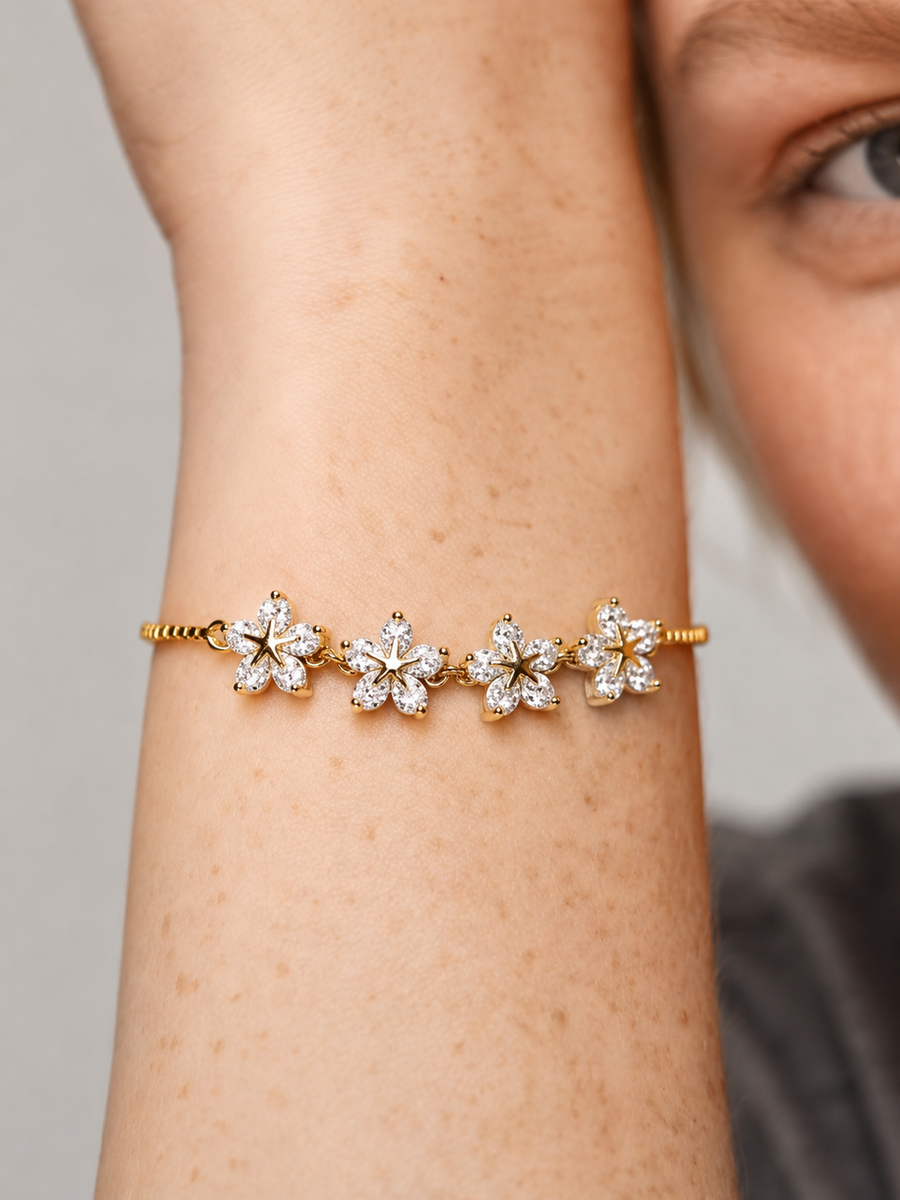 Pulseira dourada elegante com flores em cristais brilhantes e corrente fina, usada no pulso para um visual feminino, delicado e luminoso.