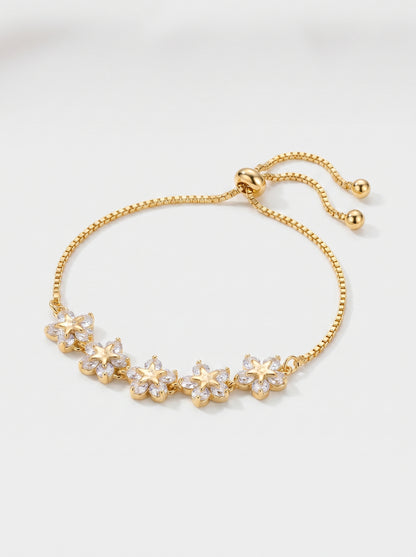 Pulseira dourada delicada com flores em cristais, corrente ajustável e acabamento brilhante, fotografada sobre fundo claro para um visual feminino, elegante e luminoso.