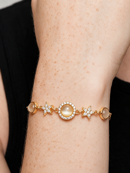 Pulseira dourada elegante com cristais brilhantes, detalhes em estrela e pendente circular central, usada no pulso para um visual feminino, sofisticado e luminoso.