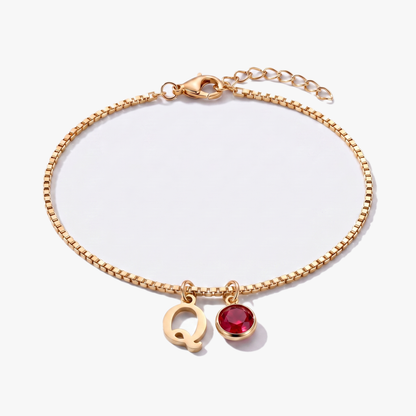 Pulseira letra Q dourada com pedra de nascimento Janeiro — Granada